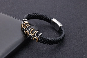 Macro detail of men's black braided leather bracelet with gold and silver magnetic clasp