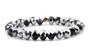 Macro shot of multifaceted black and silver hematite beads with one gold hex accent