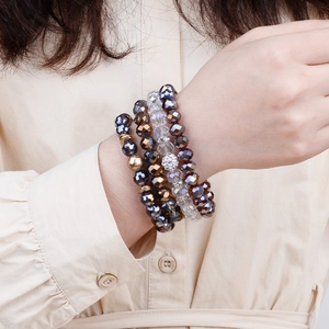 Close-up of stacked colorful crystal beaded bracelets on wrist with metal charms
