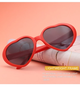 Close-up of red heart-shaped PC sunglasses placed on a magazine with warm tones