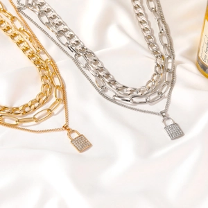Close-up of gold and silver multi-layered chunky chain necklaces with iced out lock pendants