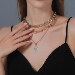 Detail of a layered gold necklace with chunky chains and a crystal-encrusted lock pendant