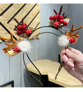 Close-up of reindeer antler headband with red berries, pine cones and white fur balls