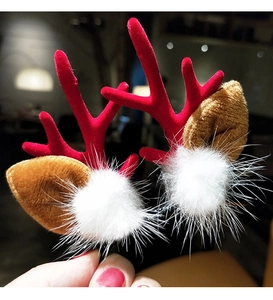 Close-up of red reindeer antler hair clips with white pom-poms for Christmas styling