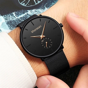 Close-up of a men's black quartz watch with gold markers and black mesh strap on wrist