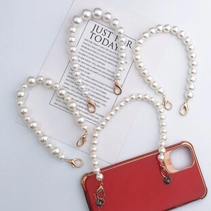 Close-up of elegant white pearl phone strap with golden alloy hooks and glossy finish