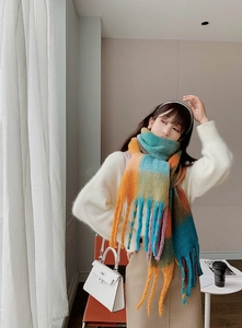 Close-up of thick winter scarf featuring colorful rainbow plaid pattern and long tassels