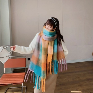 Close-up of vibrant rainbow plaid scarf showing soft texture and thick braided tassels