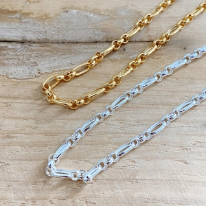 Parallel view of gold and silver bold chain choker necklaces on a wooden background