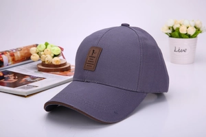 Detail of blue-grey cotton baseball cap with leather logo patch and brown brim edge