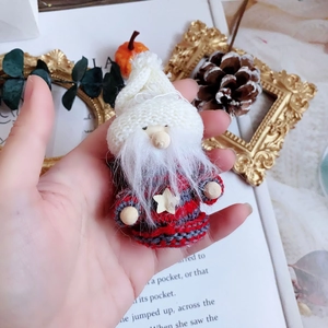 Handmade knitted Santa Claus ornament with white beard and star detail in hand