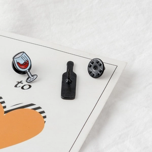 Macro shot of red wine glass enamel pin set with secure butterfly clutch on white fabric