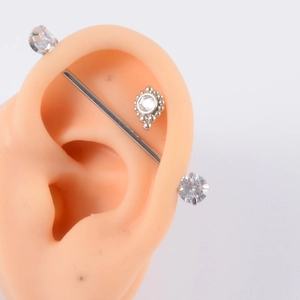 Macro detail of industrial barbell and zircon studs on realistic silicone ear model