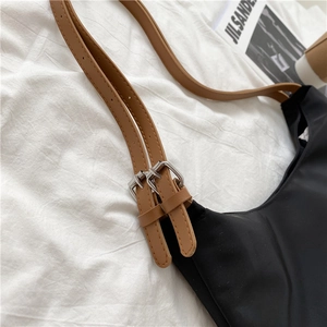 Detail of adjustable brown faux leather straps with silver metal buckles on a black tote bag