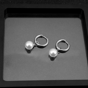 Close-up of classic polished stainless steel hoop earrings with white faux pearls