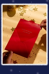 Gros plan d'une carte de Noël rouge avec texte doré et étoiles scintillantes