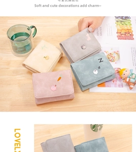 Detail of four candy-colored tri-fold wallets with cute animal embroidery on wood background