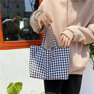 Close-up of model holding a black and white checkered canvas handbag by the window