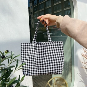 Detail of minimalist black and white checkered linen handbag held against outdoor wall