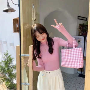 Detailed shot of pink slim-fit turtleneck knit top paired with plaid tote bag