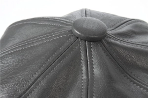 Detailed top view of a grey leather newsboy cap showing fine stitching and top button