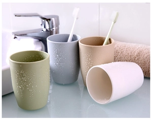 Detailed view of four minimalist bathroom tumblers in soft pastel colors on a vanity