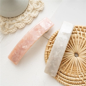 Detailed macro view of acetate hair clips showing marble texture and spring mechanism