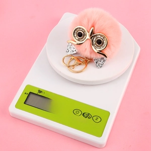 Pink owl faux fur ball keychain showing lightweight 26.0g measurement on a scale