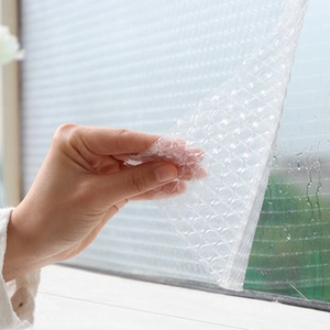 Detail of self-adhesive bubble textured privacy window film with water droplets showing texture