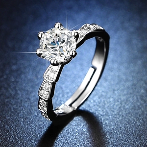 Classic silver six-prong engagement ring with large moissanite center stone on blue surface