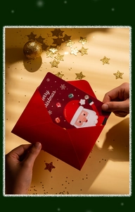 Close-up of hands pulling a red Santa Claus Christmas card out of its matching red envelope