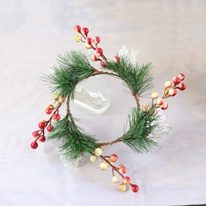 Artificial Christmas candle ring with pine needles and red berries on a glass bottle