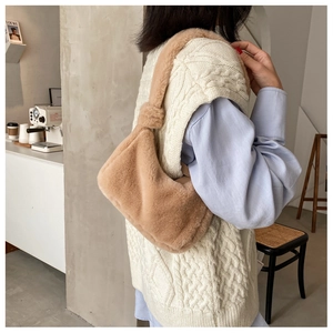 Close-up of a warm khaki faux fur shoulder bag worn with a white knit vest and blue shirt