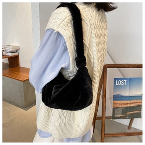 Gros plan d'un sac hobo en fausse fourrure noire avec nœud décoratif sur la bandoulière