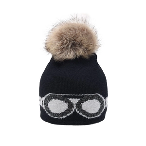Black knit beanie with brown faux fur pom pom and silver glasses pattern for winter warmth