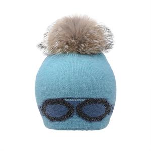 Détail du bonnet en tricot bleu avec pompon en fausse fourrure et motif lunettes pailleté
