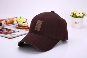 Detail of dark brown cotton baseball cap with leather EDIKO brand patch on crown