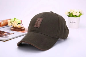 Detail of olive canvas baseball cap with brown leather trim and outdoor logo patch