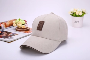 Detail of light khaki baseball cap with a brown leather patch on a stylish wooden tray