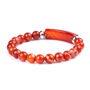 Macro shot of red agate beads and rectangular stone plaque on a beaded bracelet
