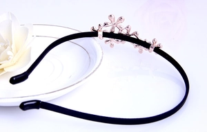 Close-up of black headband featuring rose gold metallic flowers on a clean white surface