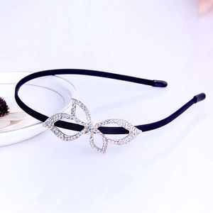 Detail of a black metal headband featuring a crystal-studded bow with rhinestone accents