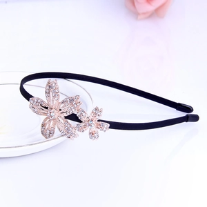 Close-up of rose gold rhinestone flowers on a black headband with elegant crystal detail