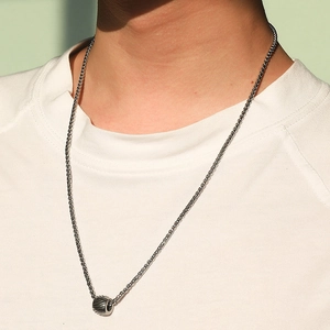 Detail of a men's stainless steel cylindrical totem bead pendant on a woven chain necklace