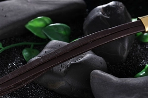 Close-up of vintage leather bracelet with anchor charm and gold metal details