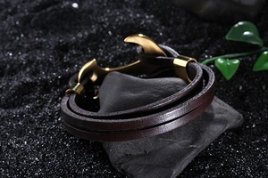 Detail of a men's double-wrap dark brown braided leather bracelet with a gold anchor clasp