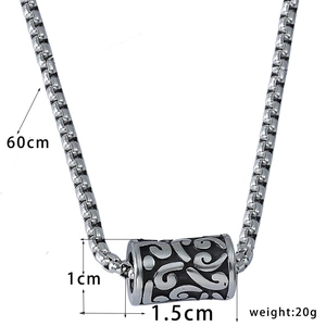 Macro detail of silver-toned stainless steel pendant with etched floral scroll patterns