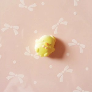 Detail of a yellow resin chick charm with pink bowknot for DIY craft and phone case decor