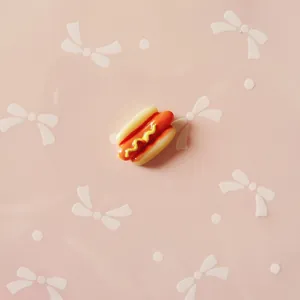 Realistic resin hot dog charm for DIY crafts with glossy finish on a pink background