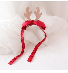 Close-up of Christmas reindeer hair clip with golden antlers and red glitter ribbons